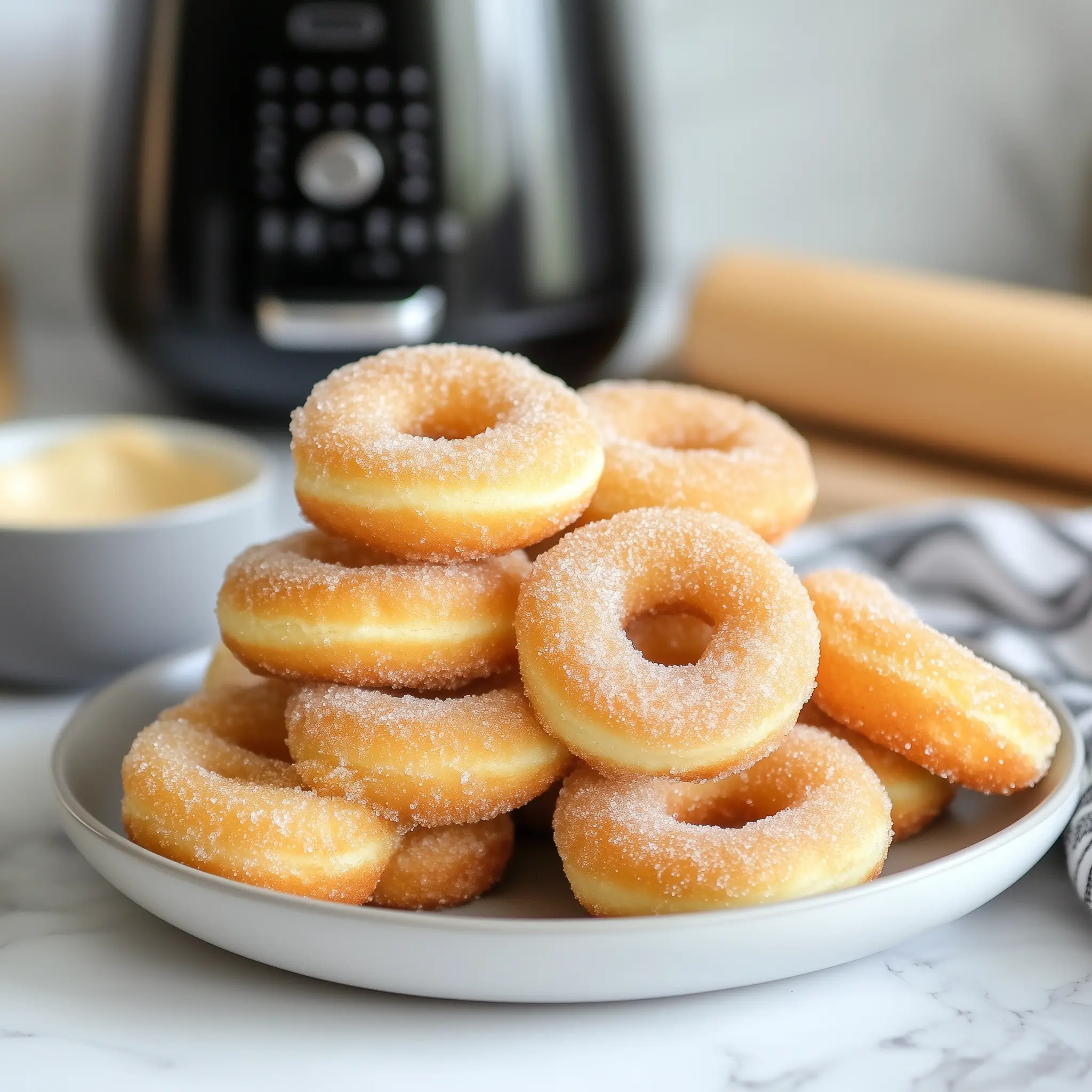 donuts op een bord met in de achtergrond een airfryer.