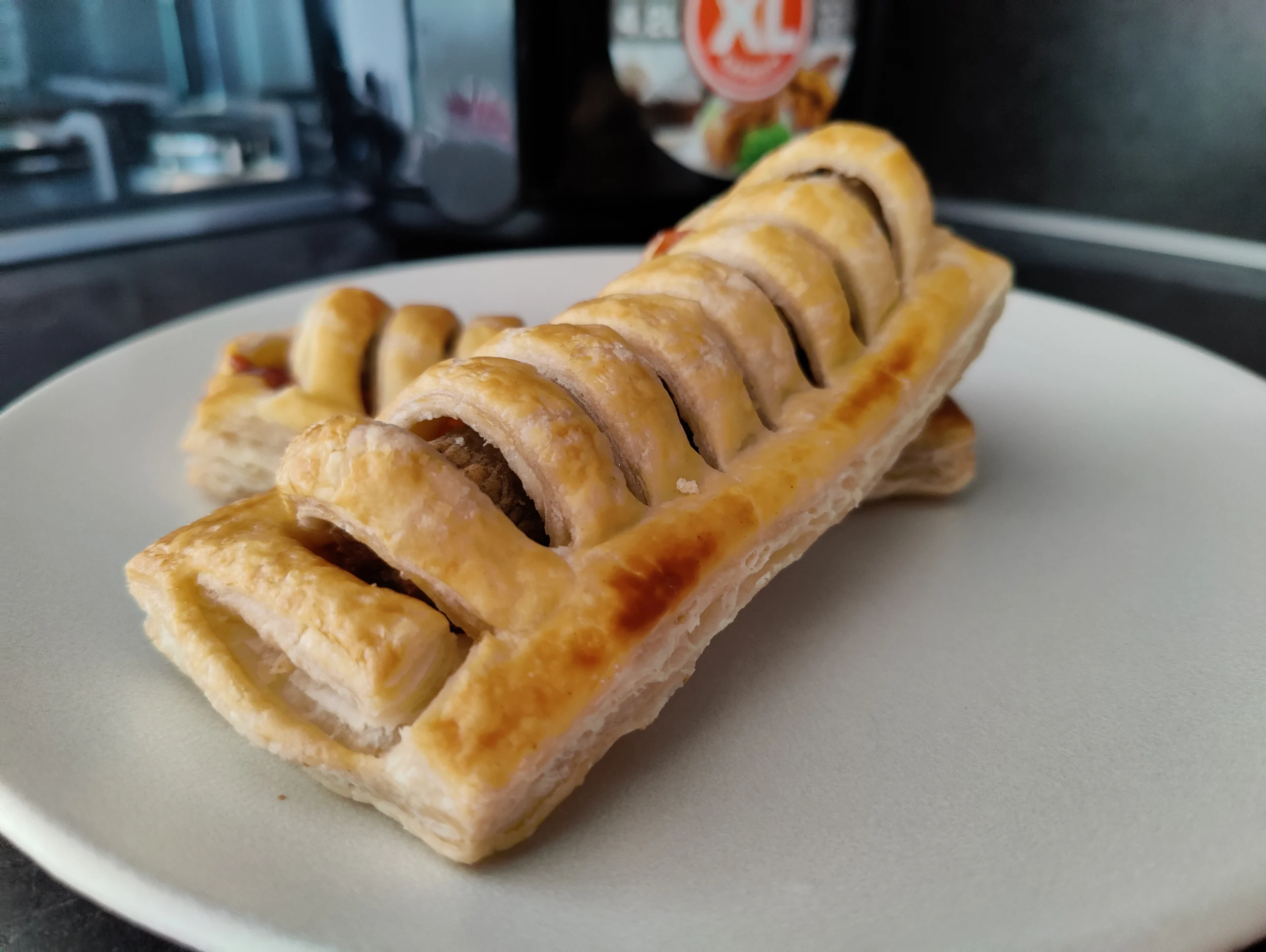frikandelbroodje op een bord met in de achtergrond een airfryer.